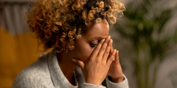 Anxious woman holding with hands folded in front of face